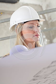 Una mujer o construcción un ingeniero lectura dibujo técnico la ropa casco adentro el edificio paginas andamio en 