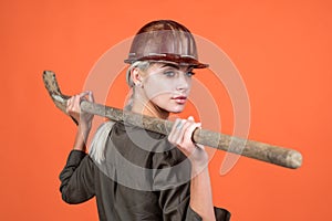 woman architect in protective helmet and boilersuit hold shovel on orange background, building