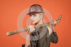 woman architect in protective helmet and boilersuit hold shovel on orange background, building