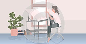 woman architect sitting at workplace with adjustable drawing board desk