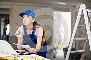 Woman architect using laptop at renovating apartment