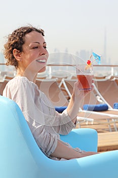 Woman in armchair on cruise liner with cocktail