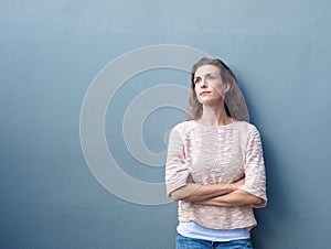 Woman with arms crossed looking away with thoughtful expression