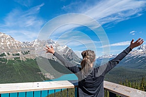 Woman with arms outstretched views Peyto Lake in Banff National Park