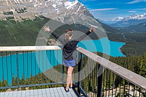 Woman with arms outstretched views Peyto Lake in Banff National Park