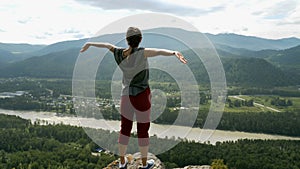 Woman with arms raised on top of mountain