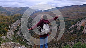 Woman with arms raised on top of mountain looking at view.