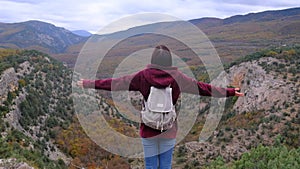 Woman with arms raised on top of mountain looking at view.