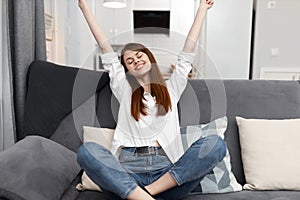 woman with arms raised up sits on the couch free time rest at home