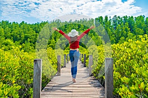 Woman with arms raised in wooden bridge at Tung Prong Thong or Golden Mangrove Field, Rayong, Thailand