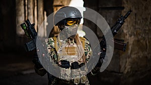 A woman in an army uniform holds a firearm in an abandoned building.