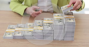 Woman arranges stacks of dollar bills neatly on table