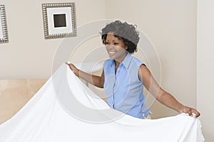 Woman Arranging Bed At Home