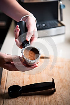 Woman arranging coffee ground powder into portafilter basket at home