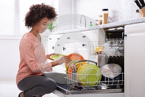 Woman Arranging Plates In Dishwasher