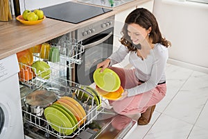 Woman Arranging Plates In Dishwasher