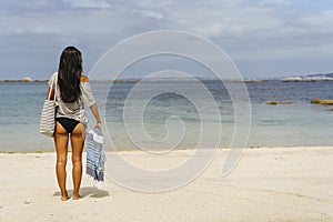 Woman arriving beach with towel, summer begins