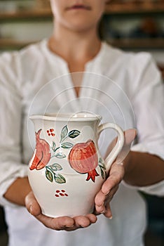 woman artisan ceramist holding a beautiful hand-painted clay jug