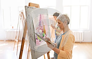 Woman artist with easel painting at art school