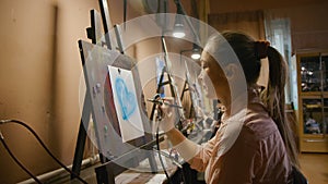 Woman artist learns to paint with airbrush with acrylic dye, paper and easel. Concept modern art, airbrushing