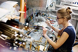 Woman artist making glass jewelry in her worksho