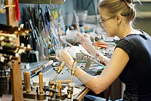 Woman artist making glass jewelry in her workshop