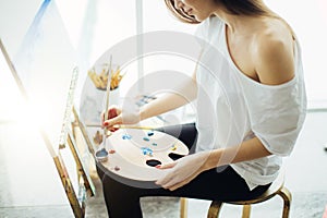 Woman artist painting a picture in a well-lit studio