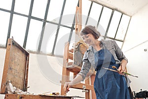 Woman artist paints a picture on canvas. Bright art studio with a large window. Easels and canvases.