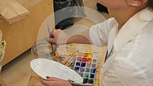 Woman artist preparing brush and watercolors to paint photo
