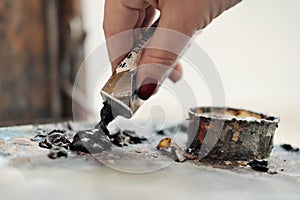 A woman artist squeezes oil paint onto a palette from a tube.