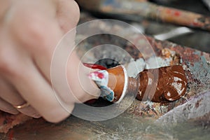 A woman artist squeezes oil paint onto a palette from a tube.