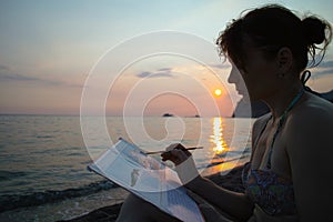 Woman artist at sunset near the sea