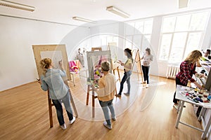 Woman artists with brushes painting at art school