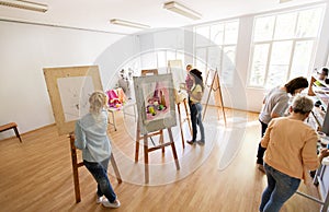 Woman artists with brushes painting at art school