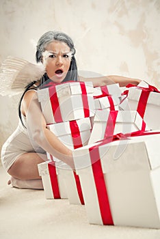 Woman as angel with heap of gift boxes indoors