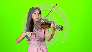 Woman of Asian appearance playing the violin. Green screen