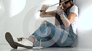 Woman of asian appearance sitting on the floor playing a violin