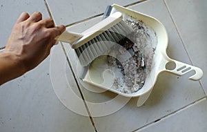 Woman asian or housekeeper sweeping tiled floor with plastic whisk broom and dustpan indoors.close up.
