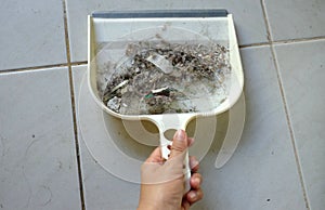 Woman asian or housekeeper sweeping tiled floor with plastic whisk broom and dustpan indoors.close up.