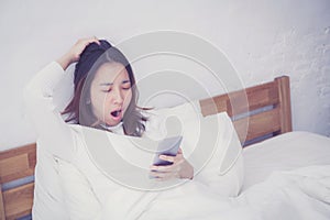 woman asian model holding a mobile phone with wake up in bedroom.