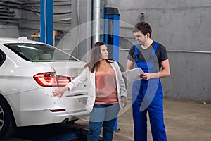 A woman asks a mechanic about a car repair