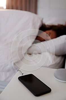 Woman Asleep In Bed With Mobile Phone On Bedside Table