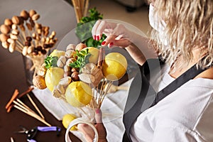 Woman assembles a fruit bouquet of lemons, nuts and mint