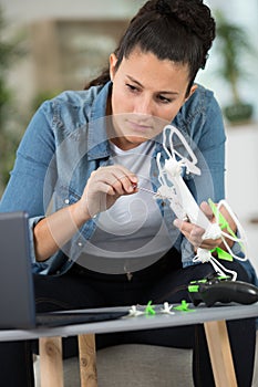 woman assembling drone following instructions on laptop