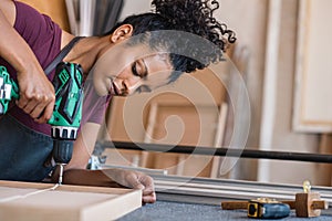 Woman assembling a frame using a drill in her workshop