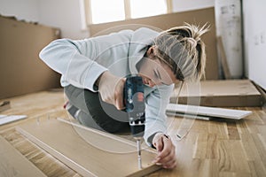 Woman assembling furniture at home