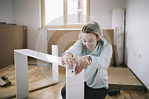 Woman assembling furniture at home