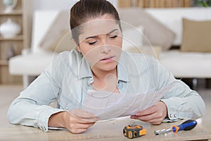 woman assembling pieces new furniture and reading instruction