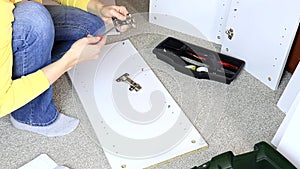 Woman assembling white furniture, she tighten a screw with a screwdriver