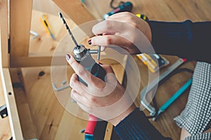 Woman assembly wooden furniture,fixing or repairing house with drill tool.modern living concepts